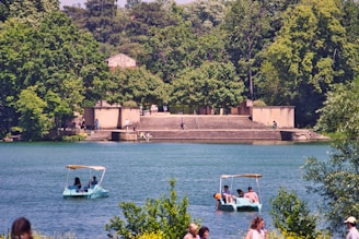 The serene shores of Lake Geneva with people enjoying paddle boating on a sunny day.