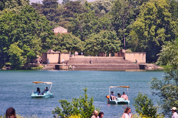 The serene shores of Lake Geneva with people enjoying paddle boating on a sunny day.