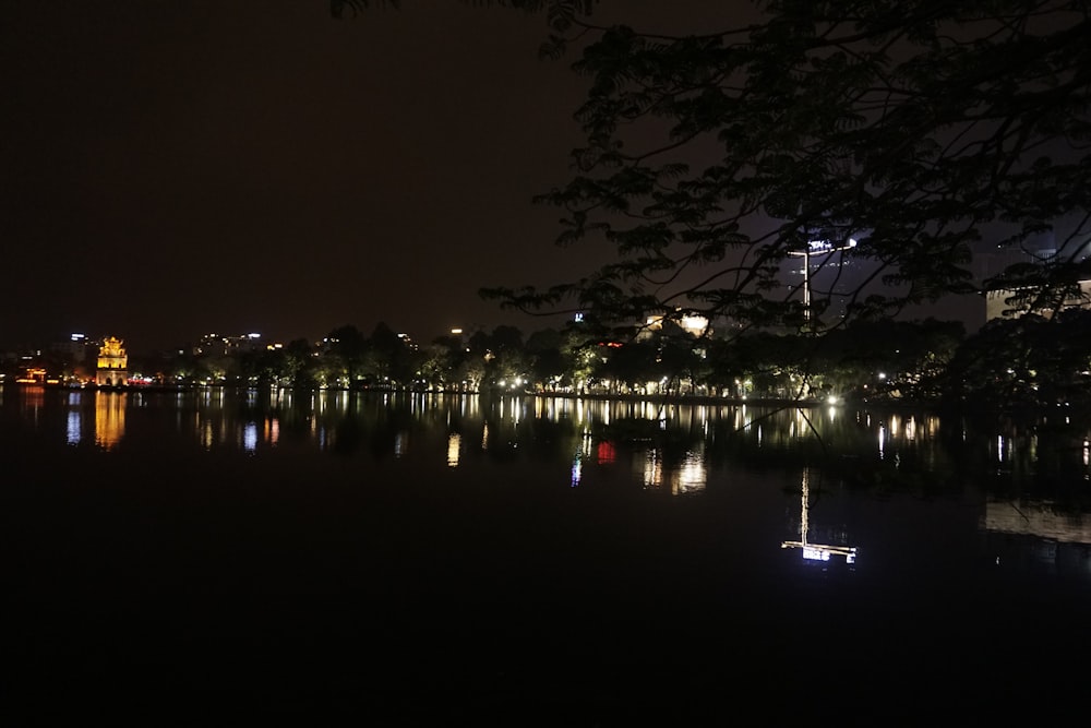 a night view of a lake with a clock tower in the distance