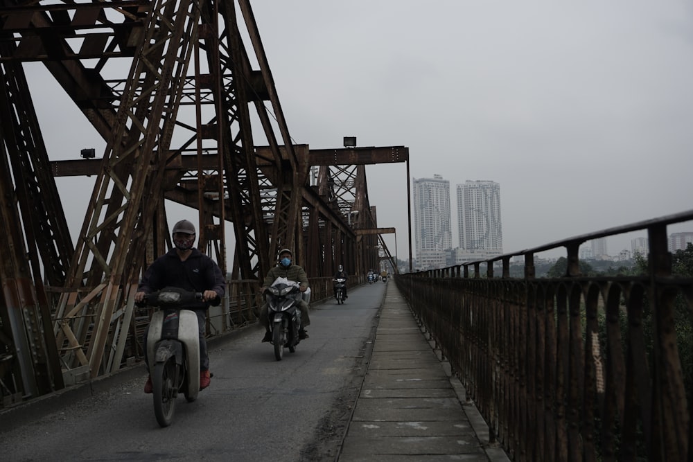 ein paar leute auf motorrädern auf einer brücke