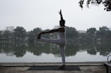 A peaceful scene of a yogi balancing on one leg beside a calm lake.