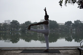 A serene yoga practitioner balancing gracefully on one leg during sunrise by the lake
