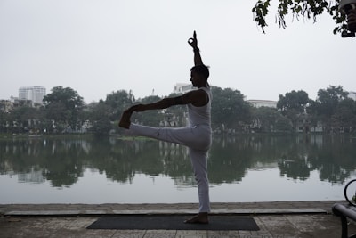 A peaceful scene of a yogi balancing on one leg beside a calm lake.