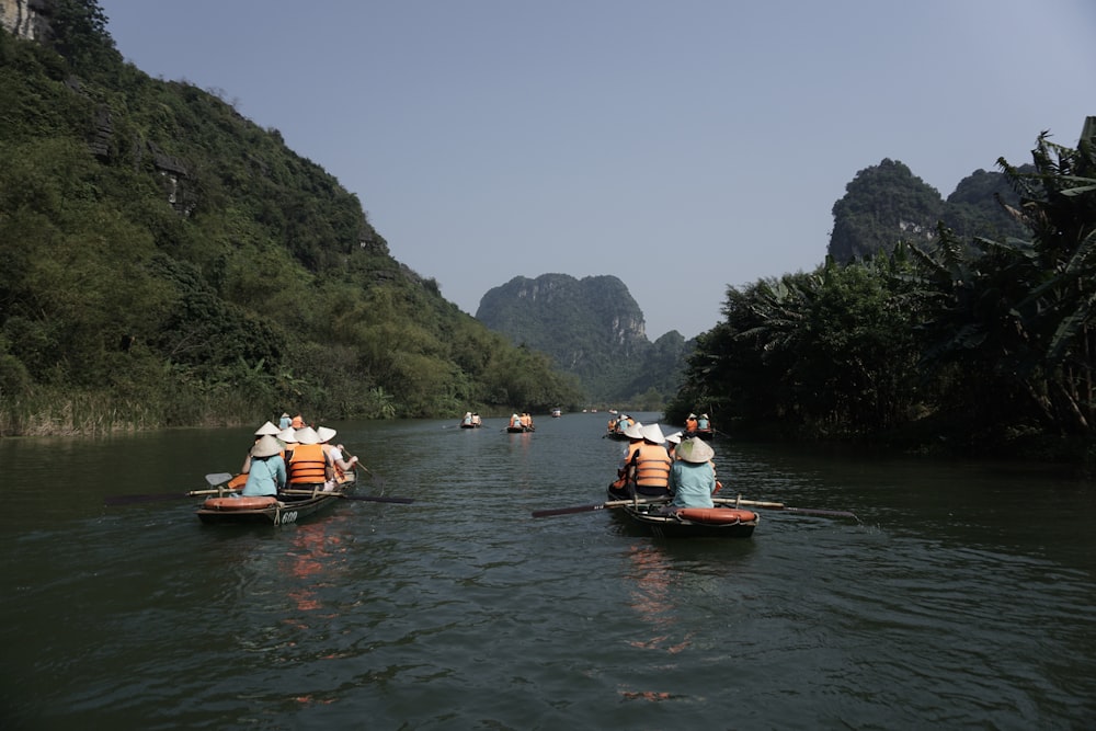 a group of people riding on the back of boats down a river