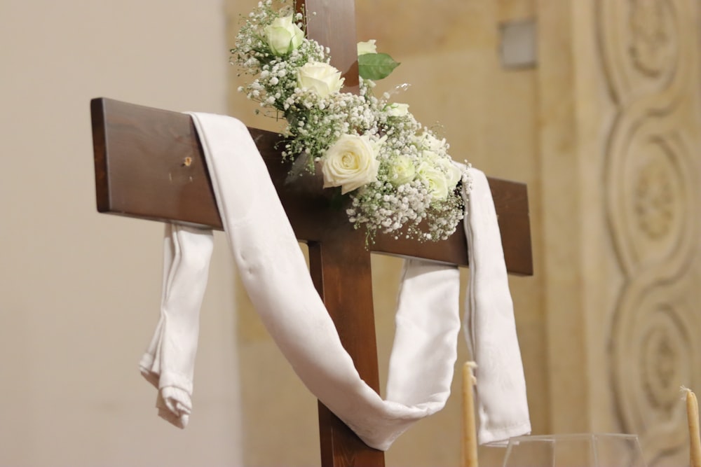 a cross decorated with white flowers and greenery