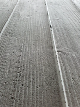 Close-up of freshly brushed concrete slab with visible texture in a large parking yard.