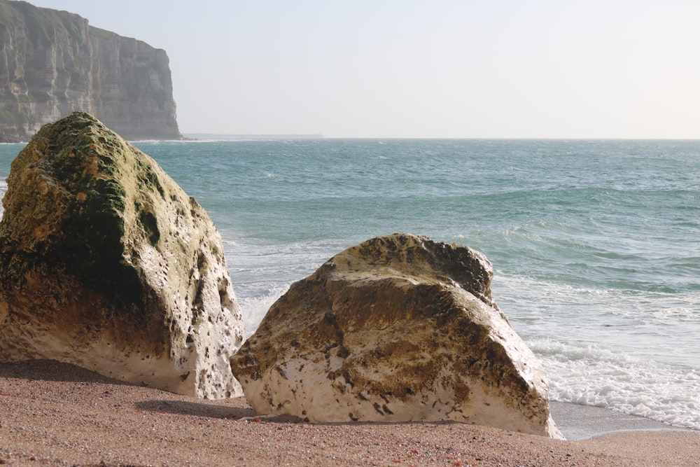 zwei große Felsen, die auf einem Sandstrand sitzen