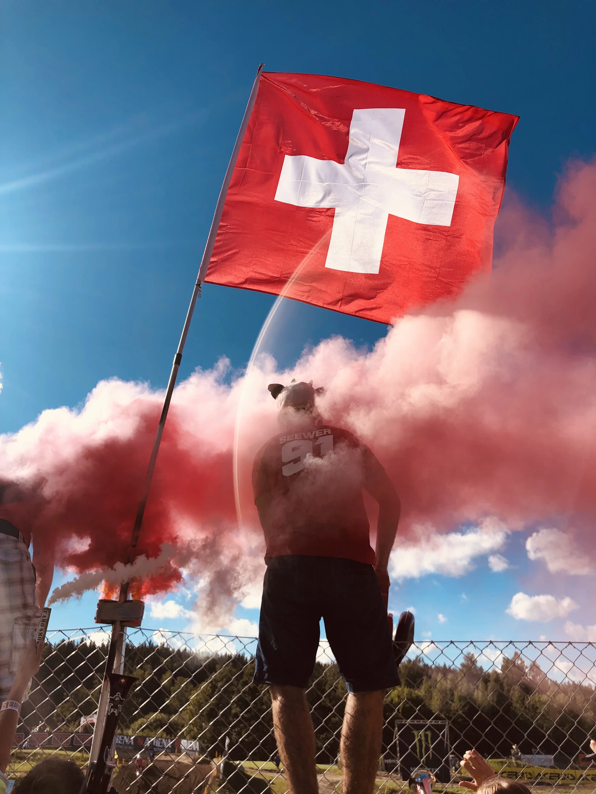 Close-up of a smiling person holding a Swiss flag, symbolizing the joy and pride of integrating into Swiss society.