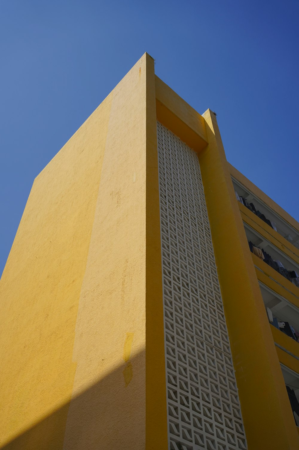 a tall yellow building with a blue sky in the background