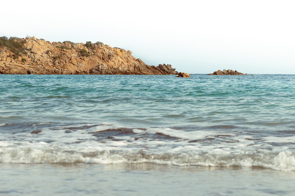 a body of water sitting next to a rocky shore