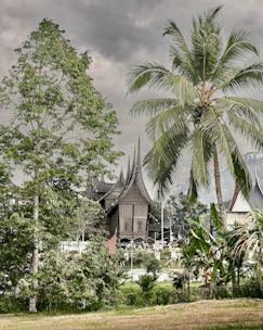 A vibrant photo of a traditional Minangkabau house with its distinctive curved roof under a bright blue sky.