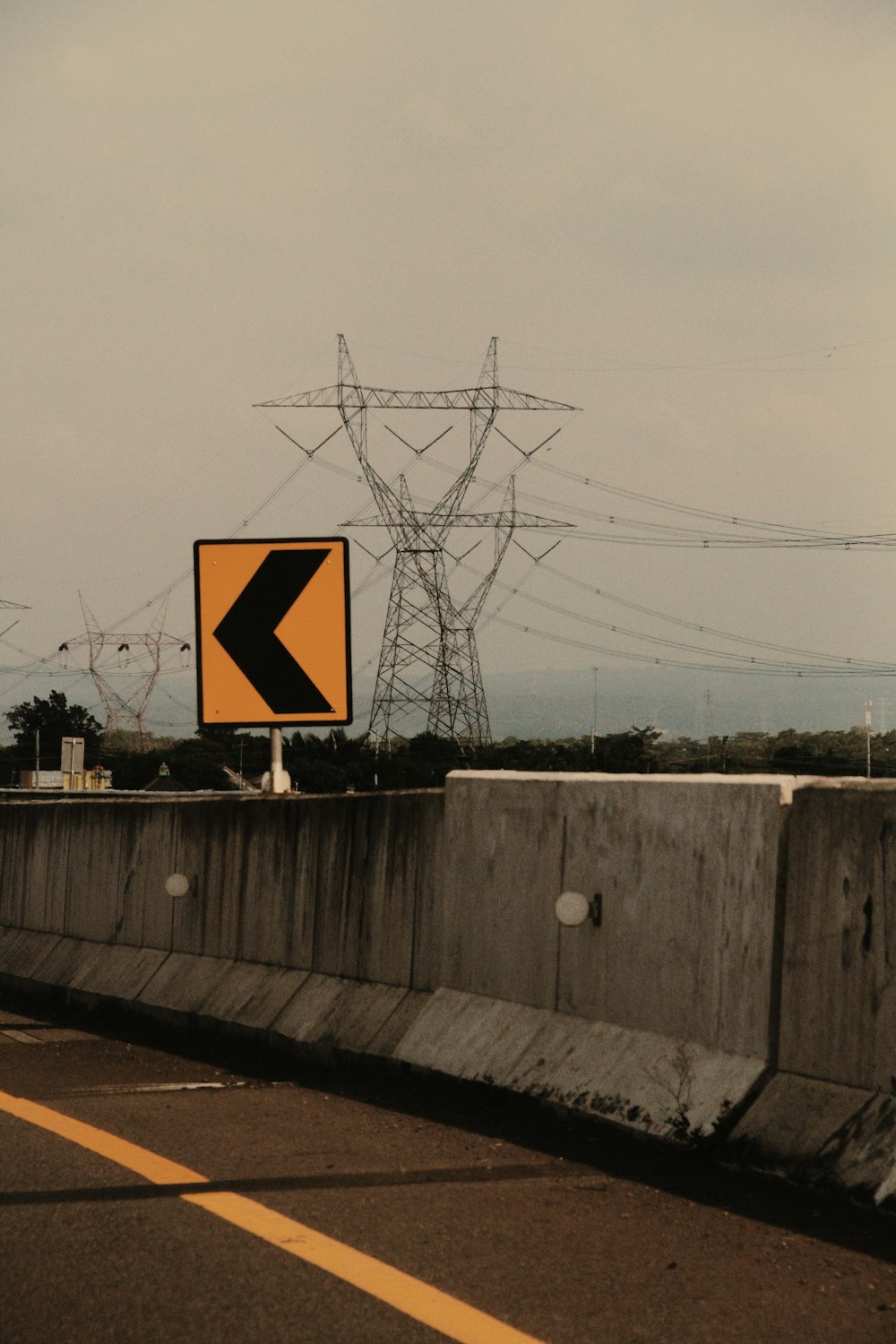 a yellow arrow sign sitting on the side of a road