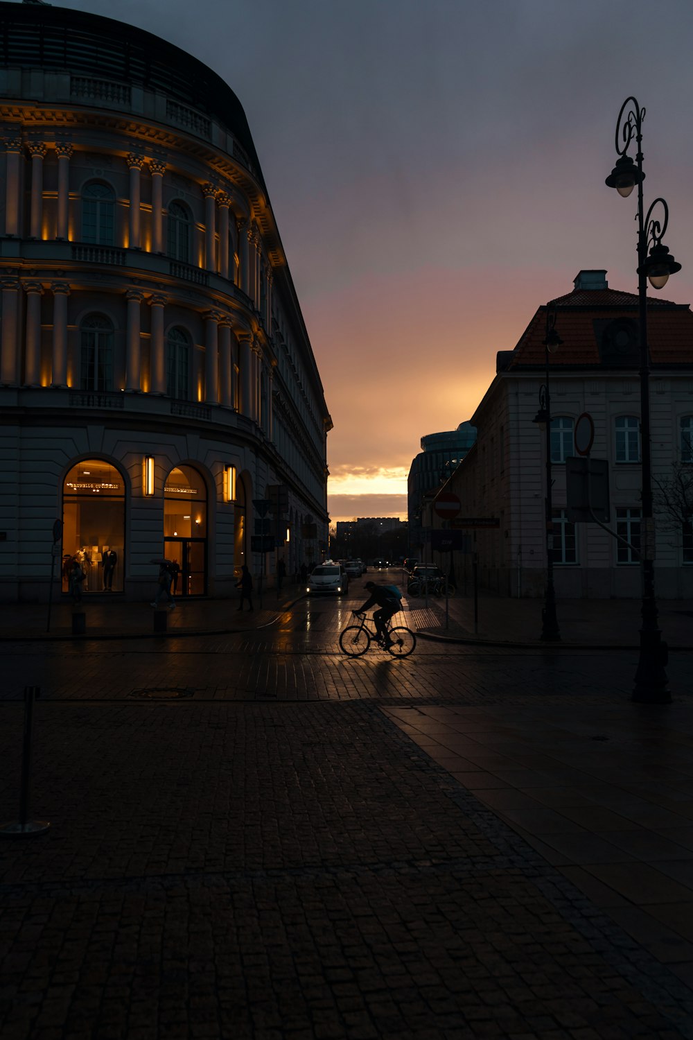 a city street at dusk with a building in the background