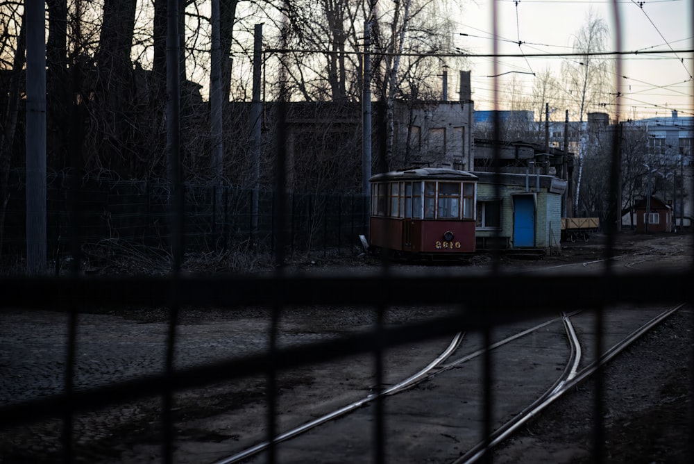 a train car sitting on the tracks behind a fence