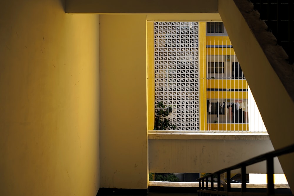 a yellow and white building is seen through a window