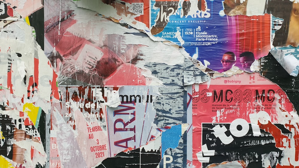 a bunch of torn up posters on a wall