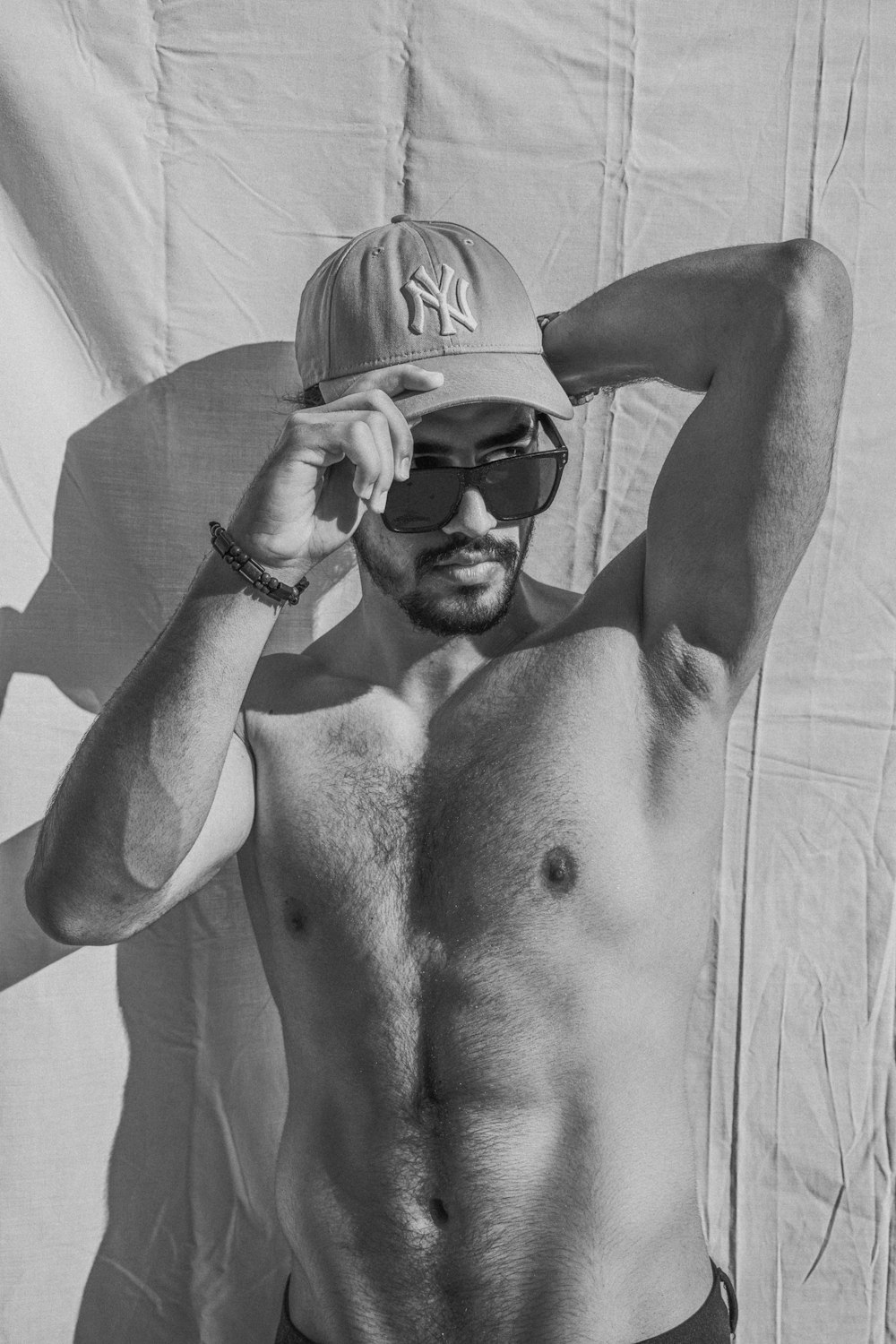 a shirtless man wearing a hat and sunglasses