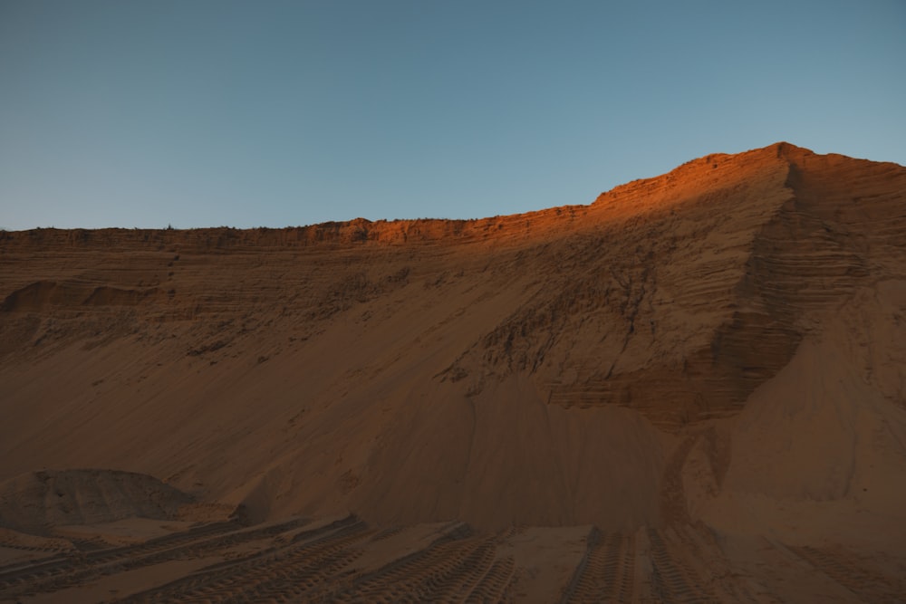 a large hill of sand with a sky in the background