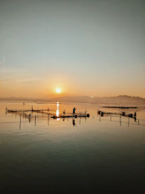Local fishermen preparing their boats at dawn with the red and green hues of the sunrise.