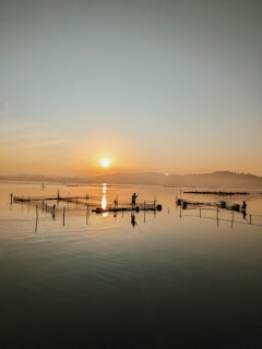 Fishermen casting nets at sunrise along a tranquil coastline.