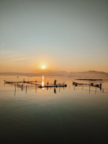 Fishermen casting nets at sunrise along a tranquil coastline.