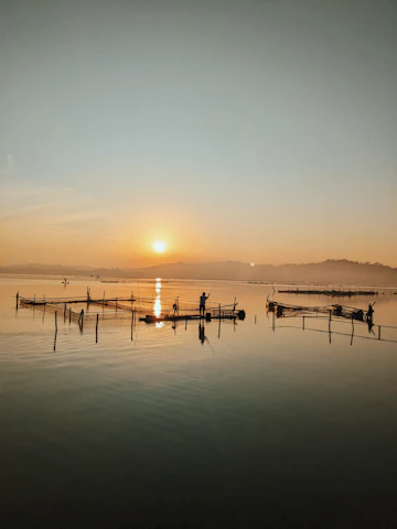 Local fishermen preparing their boats at dawn with the red and green hues of the sunrise.