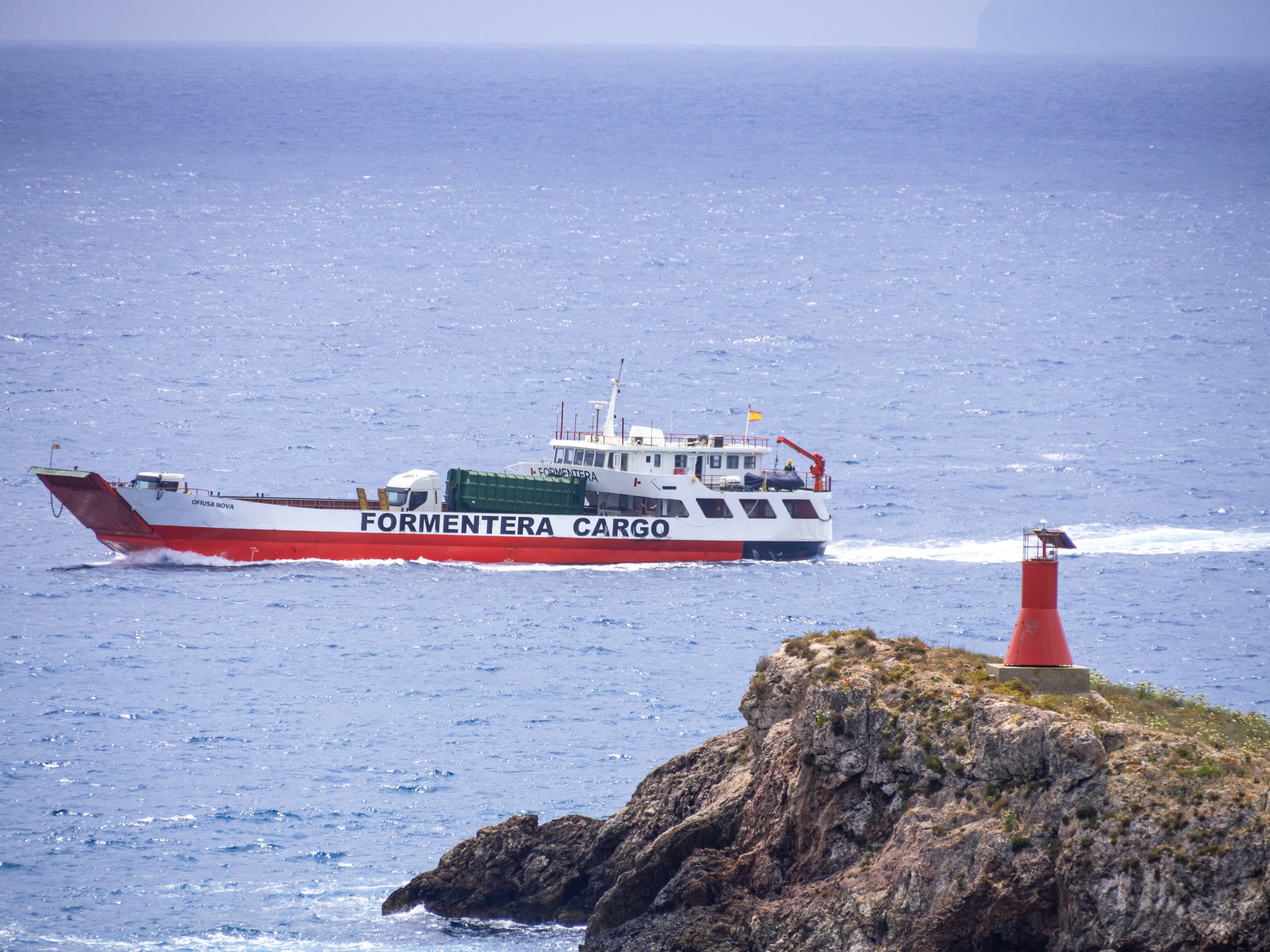 a red and white boat traveling across a body of water