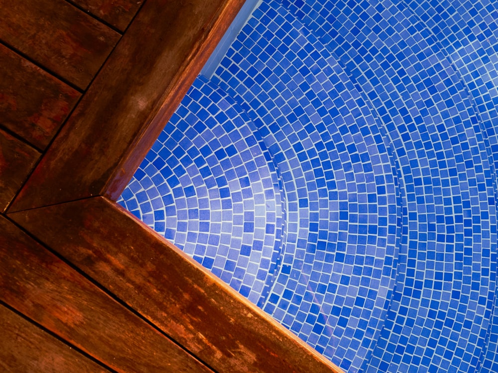 a blue swimming pool with a wooden deck