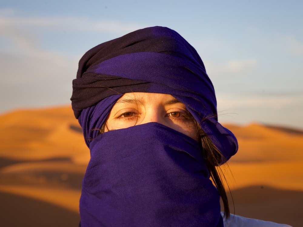 Una mujer con un pañuelo púrpura en la cabeza cubriendo su rostro