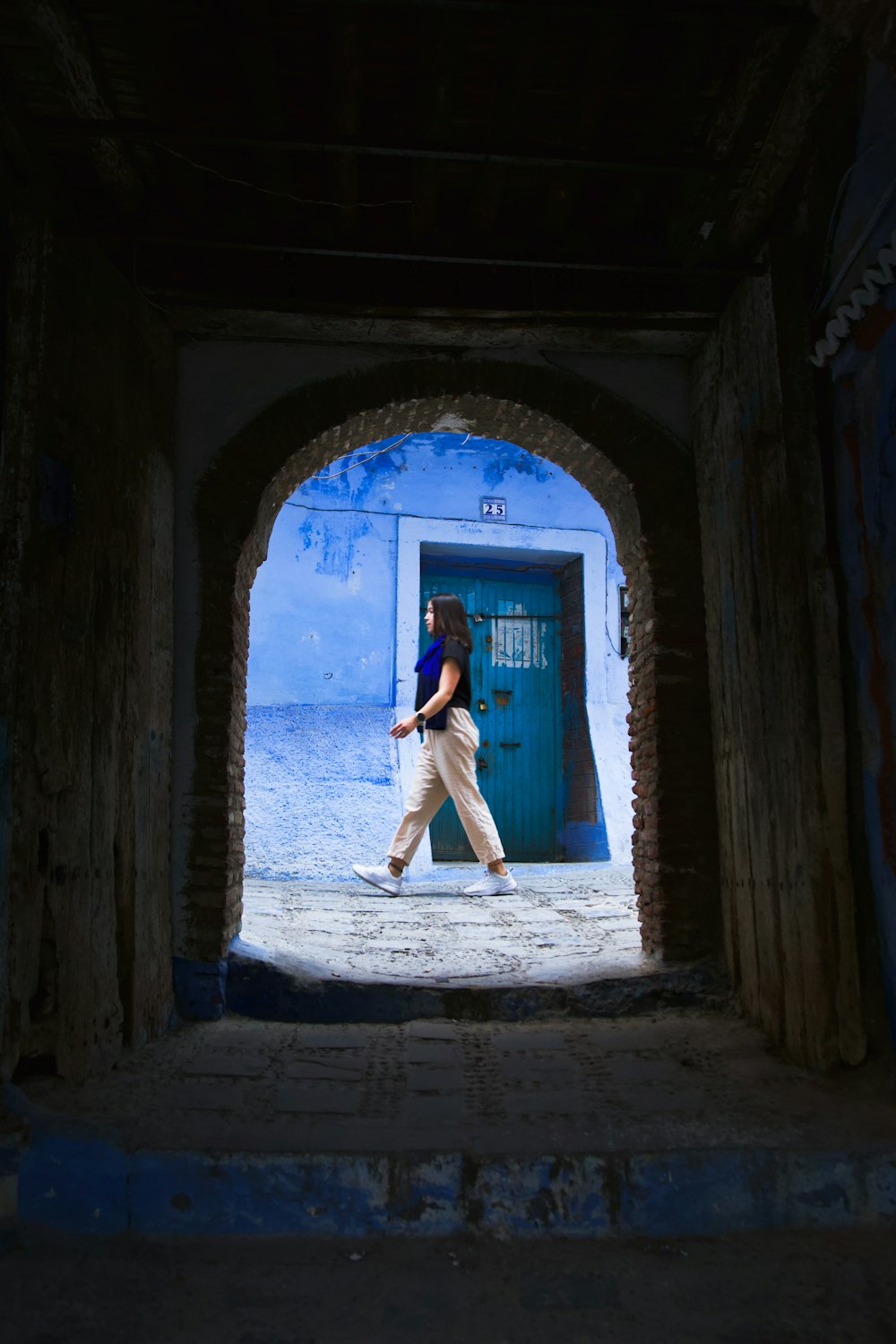 uma mulher caminhando por um túnel com uma porta azul