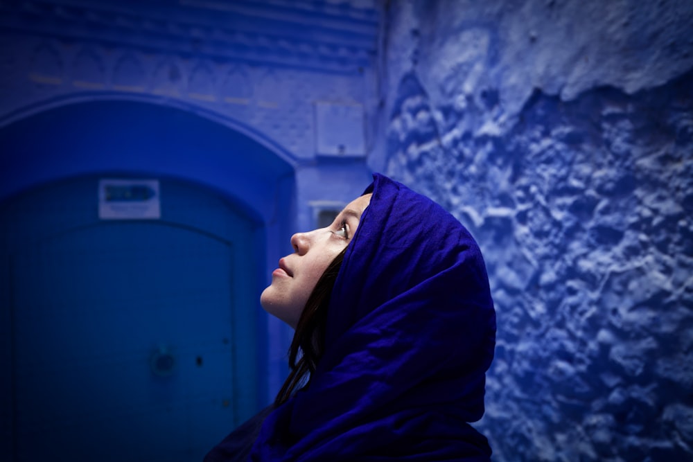 a woman in a blue hooded jacket standing in front of a blue door