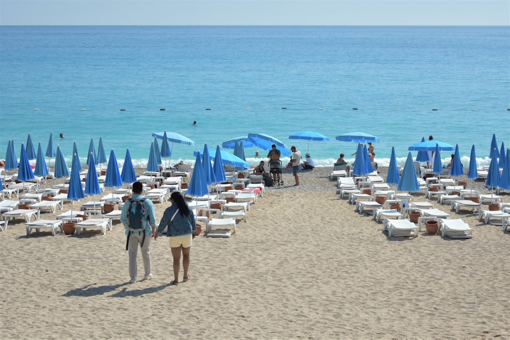 a couple of people walking down a sandy beach