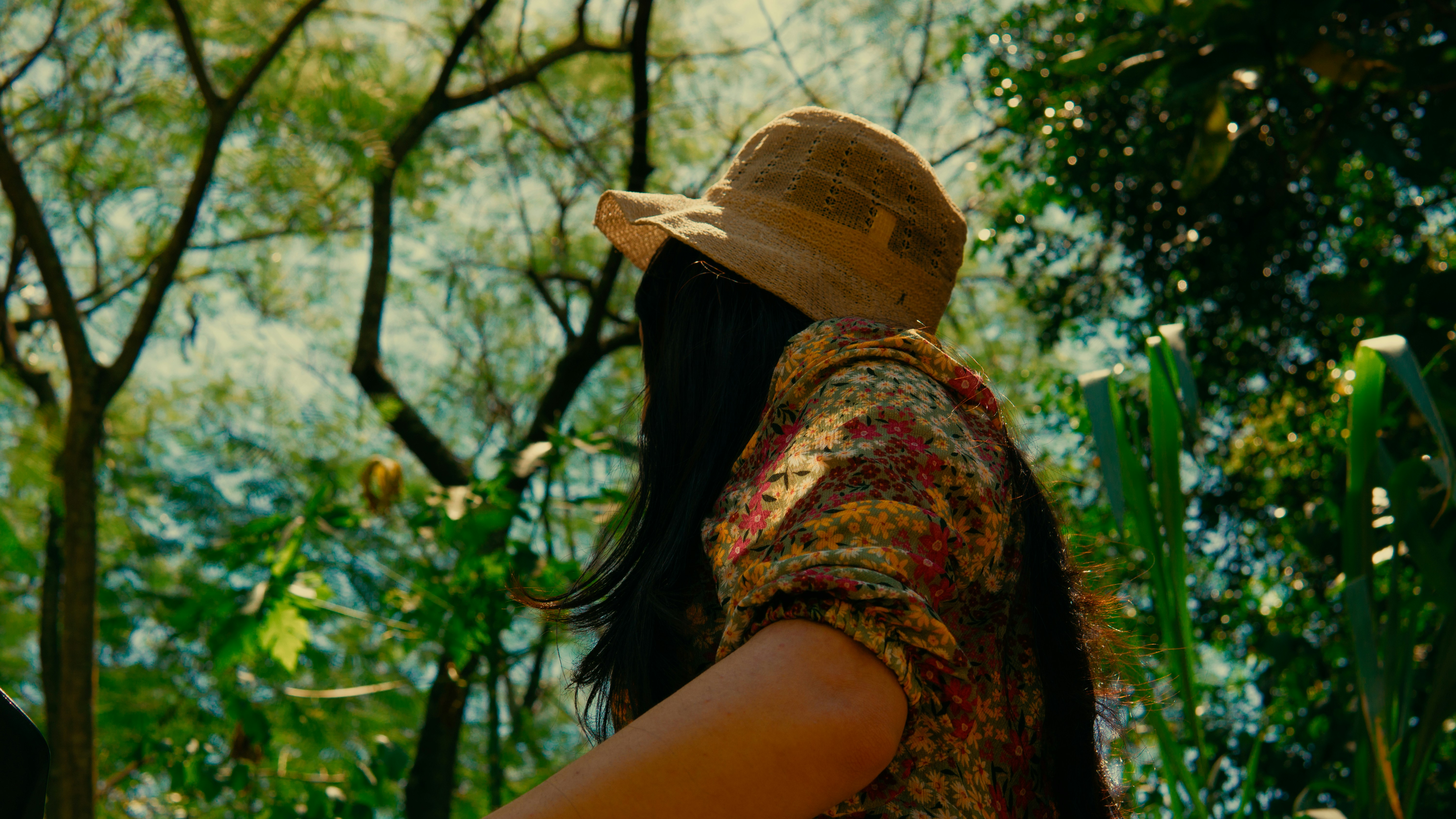 a woman wearing a hat standing in a forest