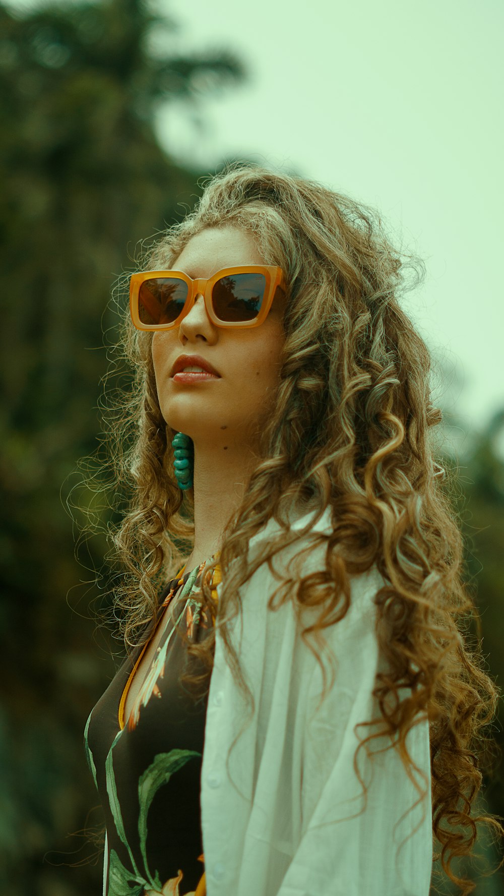 a woman with long curly hair wearing sunglasses