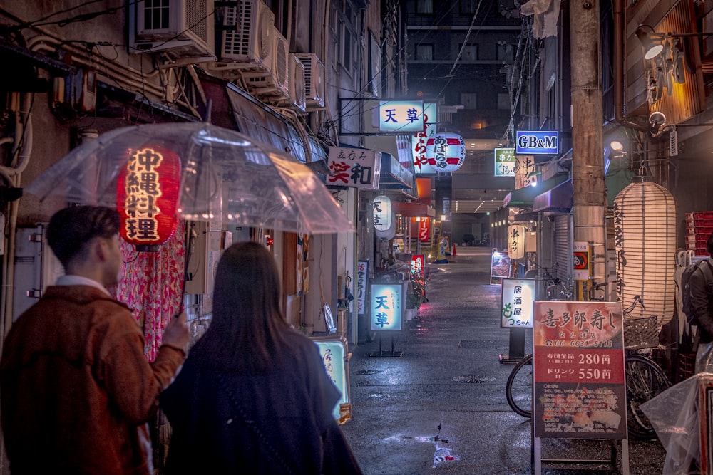 a couple of people walking down a street holding umbrellas