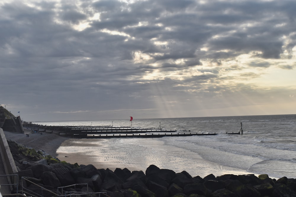 a pier on the beach with a person walking on it