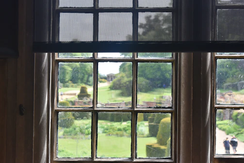 A sparkling clean window reflecting a sunny sky with a manicured lawn.
