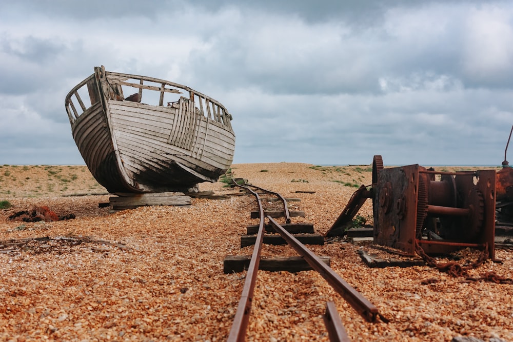 a boat sitting on top of a beach next to a train track