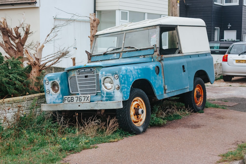 an old blue truck parked on the side of a road