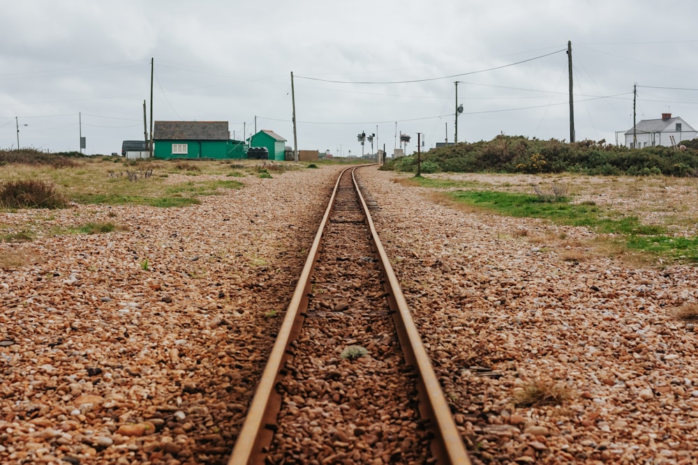 a train track with a green house in the background