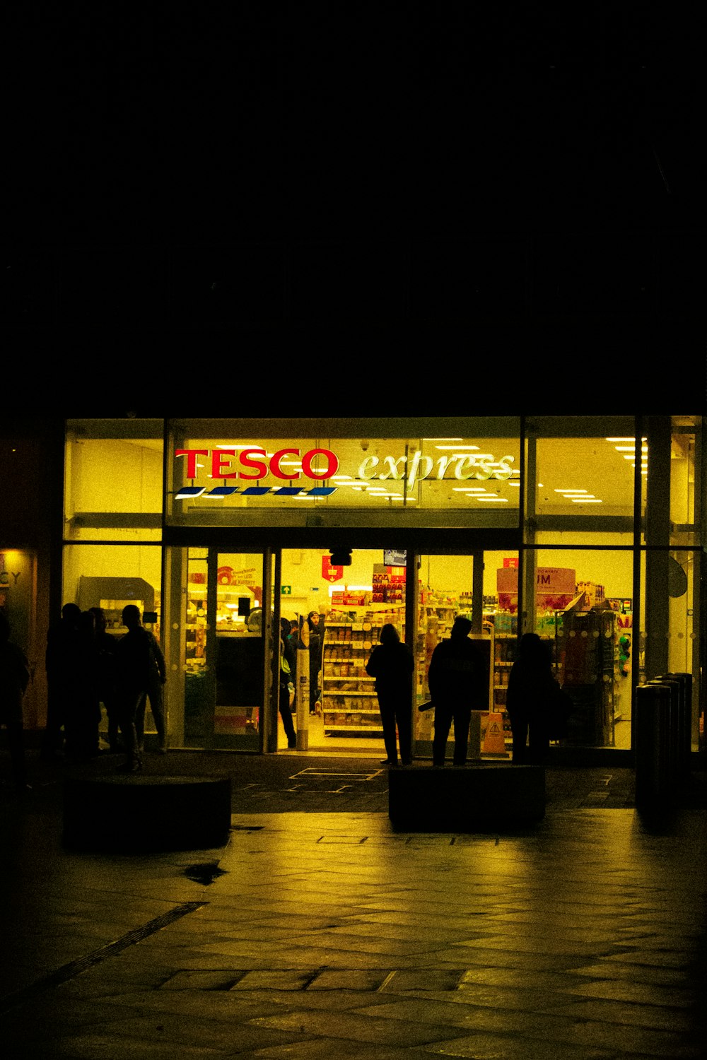 a group of people standing outside of a store at night