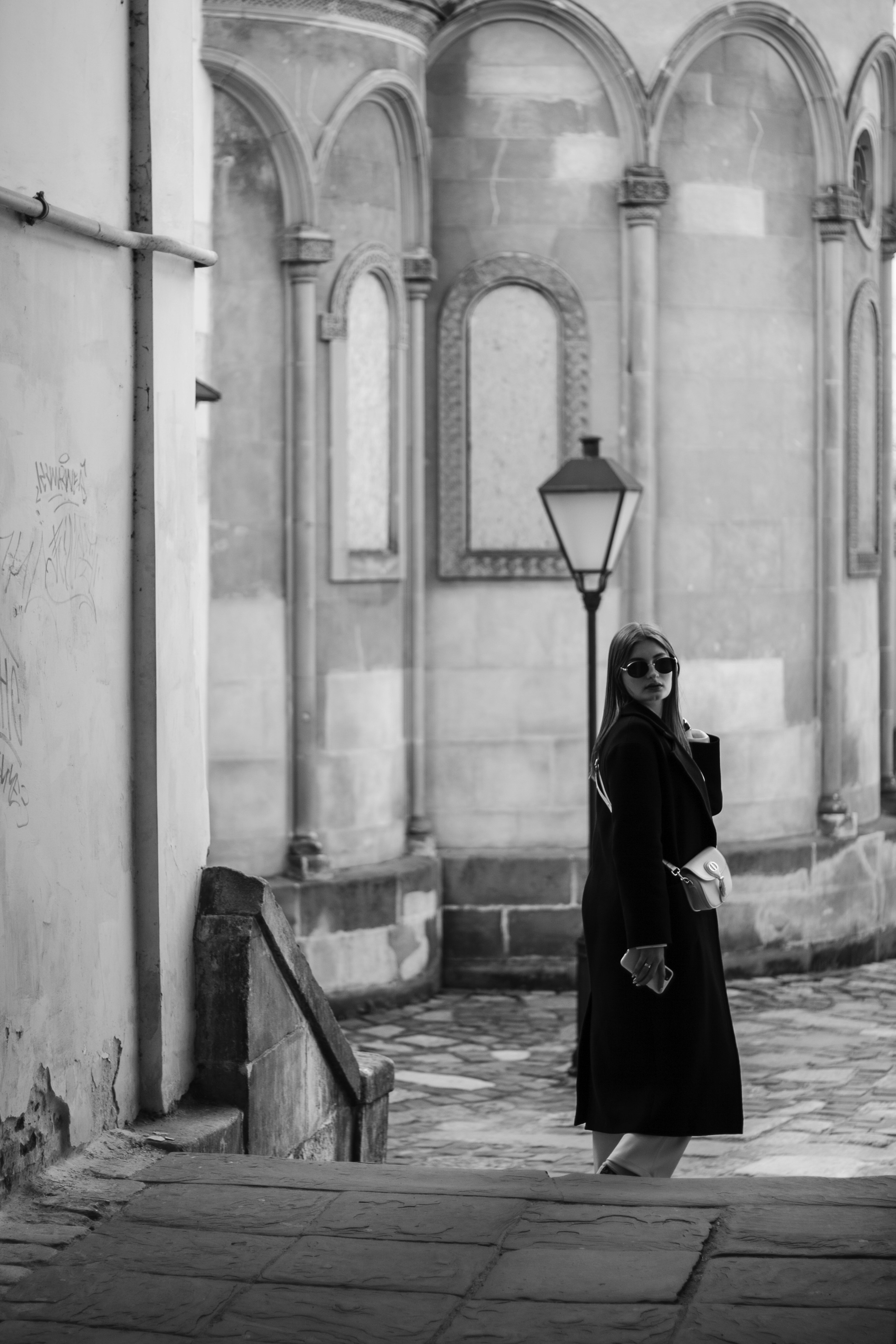 a woman in a black coat is walking down the street