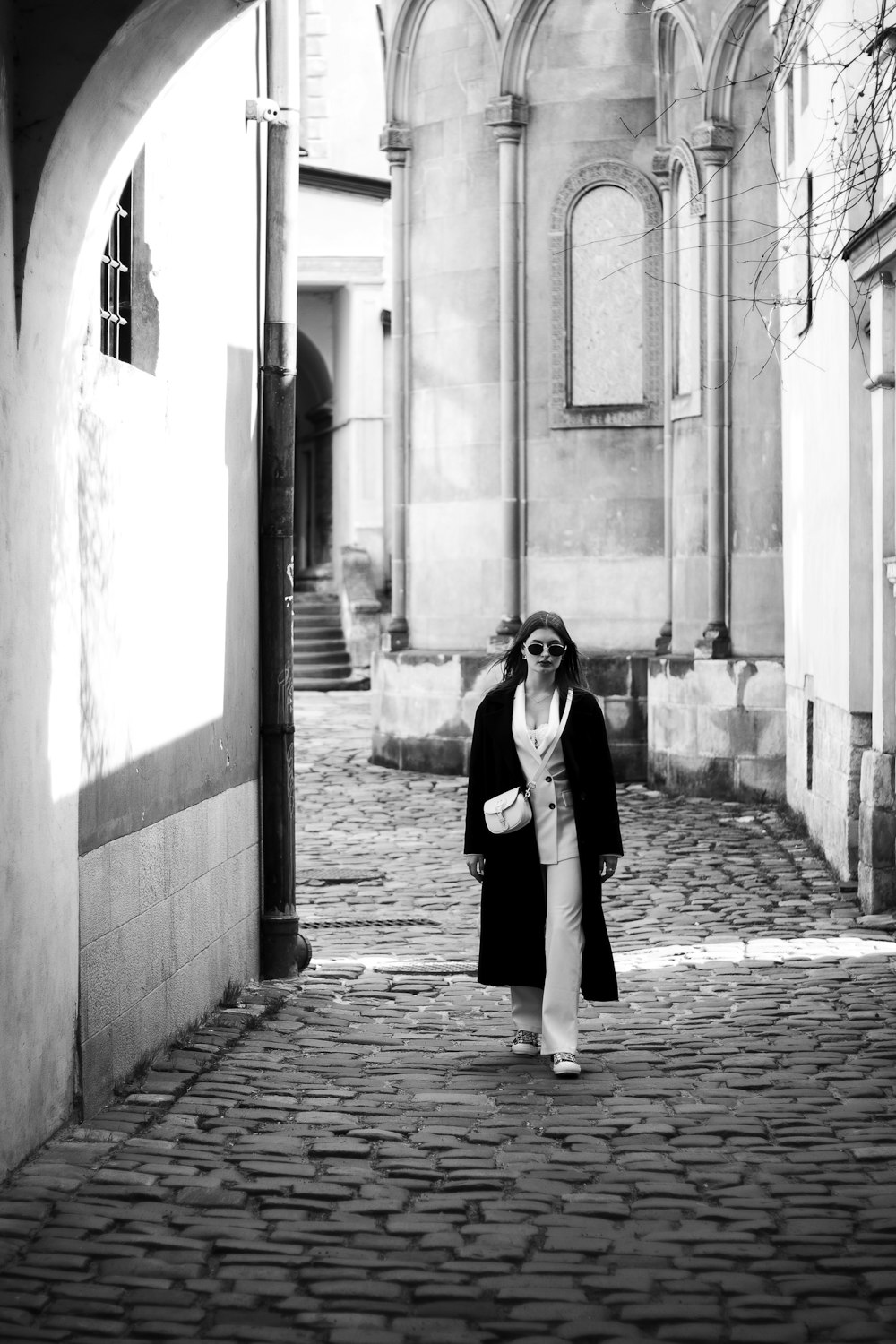 a woman is walking down a cobblestone street