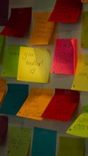 Colorful sticky notes arranged on a wall with motivational words.