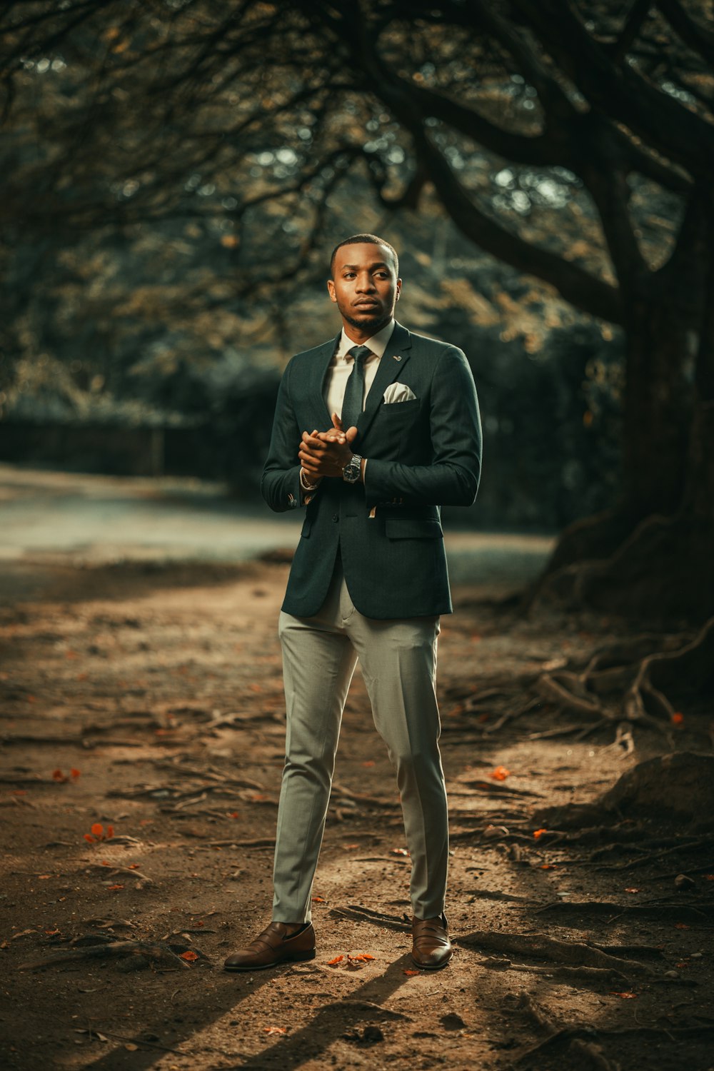 a man in a suit standing in front of a tree