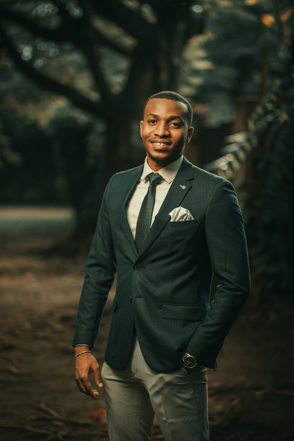 a man in a suit standing in front of trees