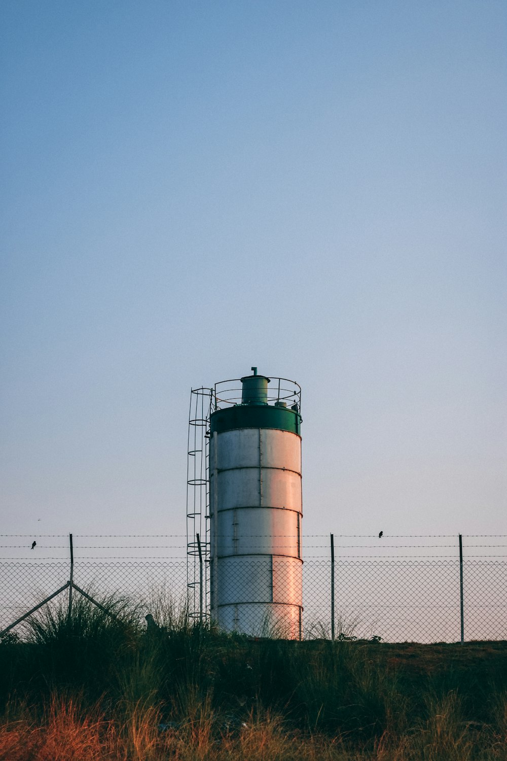 a large metal silo sitting on top of a grass covered hill