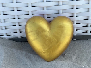 A golden heart-shaped ornament resting on a white silk cloth.