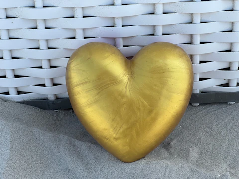 A golden heart-shaped ornament resting on a white silk cloth.