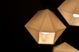 Geometric, faceted light fixtures with a modern design are illuminated against a dark background, showcasing a warm and ambient glow.
